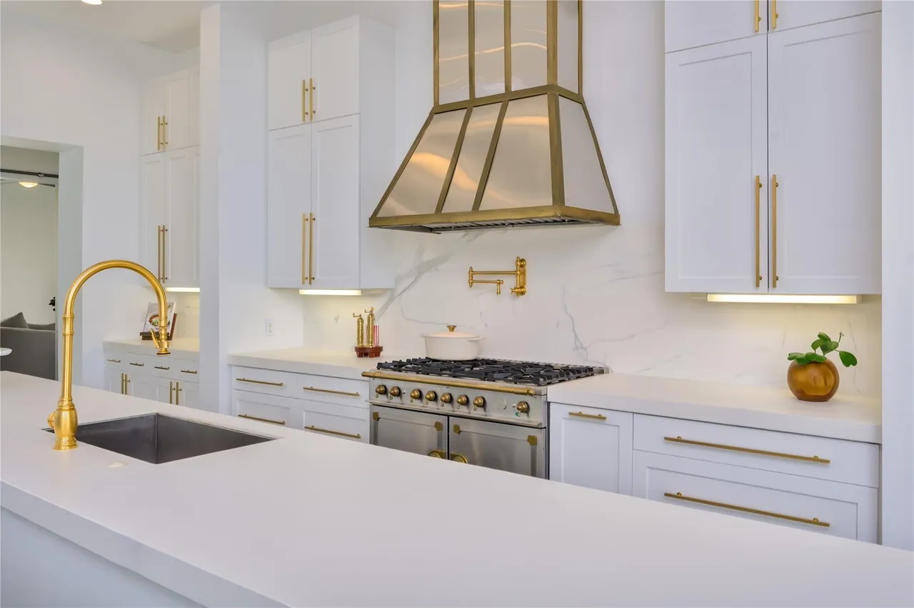 Pristine white kitchen with gold hardware and marble backsplash