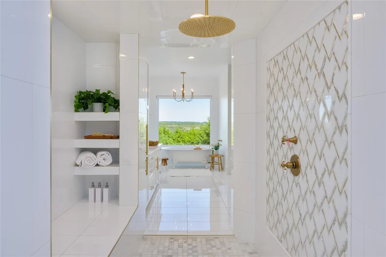 Immaculate luxury shower with gold fixtures and hill country view